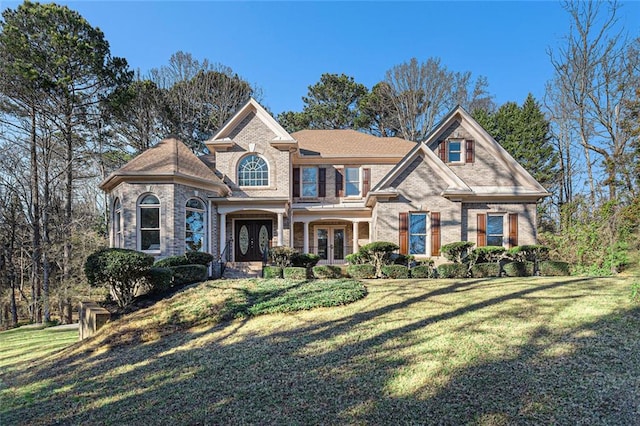 view of front of home with brick siding, a front yard, and french doors