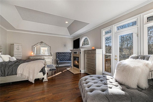 bedroom with a raised ceiling, a fireplace with flush hearth, dark wood-style flooring, access to outside, and crown molding