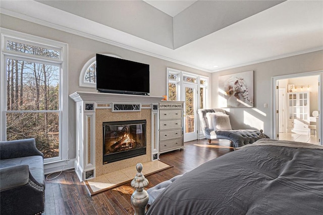 bedroom featuring crown molding, dark wood-style flooring, a fireplace, and ensuite bathroom