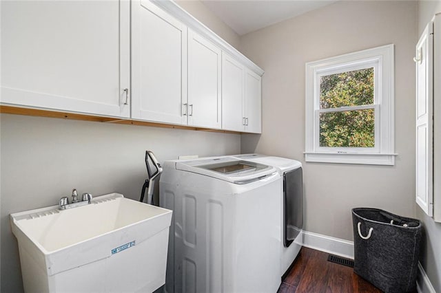 washroom with cabinet space, baseboards, dark wood-style flooring, washer and dryer, and a sink