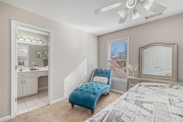 bedroom with baseboards, visible vents, a ceiling fan, light colored carpet, and ensuite bathroom