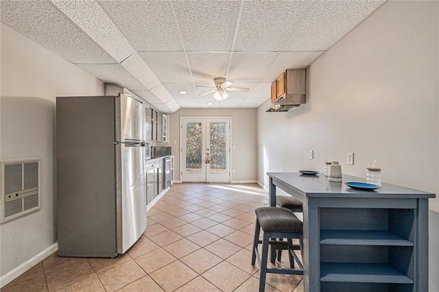 kitchen featuring stainless steel appliances, french doors, light tile patterned flooring, and a paneled ceiling