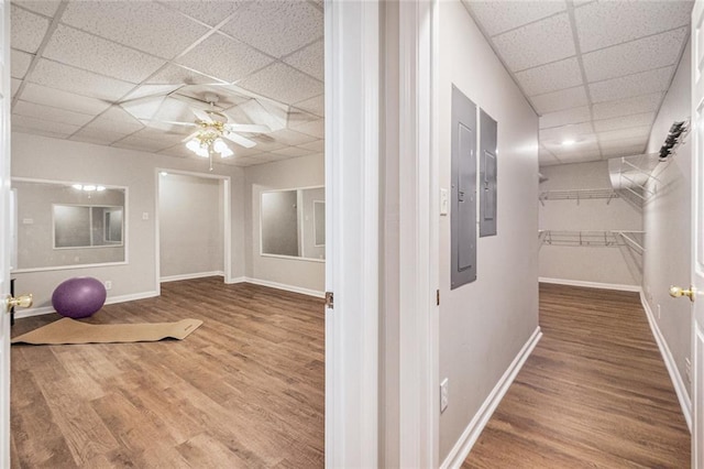 corridor featuring a drop ceiling, baseboards, and wood finished floors