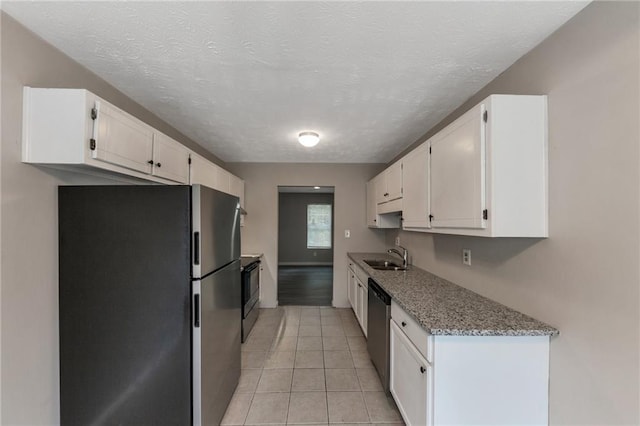 8541 Westchester Dr, Douglasville, GA 30134 - kitchen featuring appliances with stainless steel finishes, white cabinets, light tile patterned floors, light stone counters, and a textured ceiling