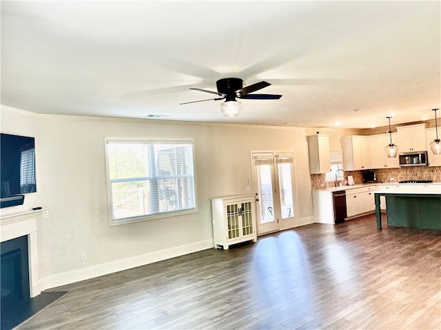 living area with plenty of natural light, dark wood-style flooring, a fireplace with flush hearth, and ornamental molding