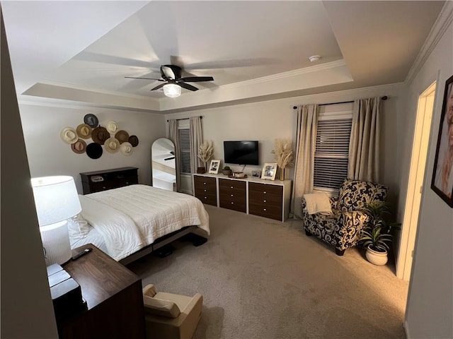 carpeted bedroom with a raised ceiling, ornamental molding, and ceiling fan