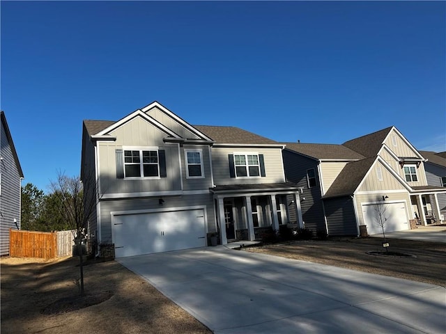 view of front facade with an attached garage, fence, board and batten siding, and driveway