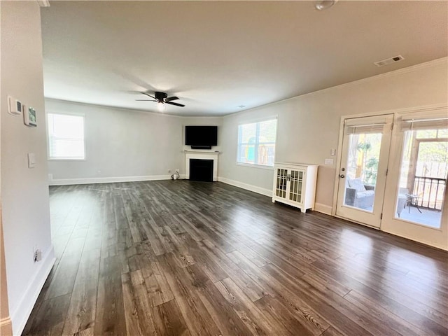 unfurnished living room featuring visible vents, baseboards, ceiling fan, a fireplace, and dark wood-style floors