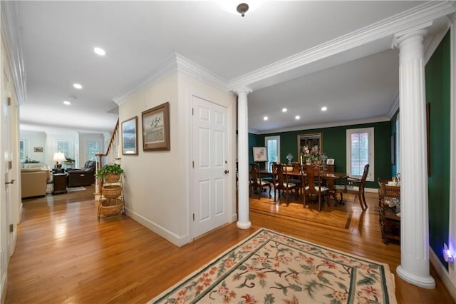 hall with crown molding, wood-type flooring, and decorative columns