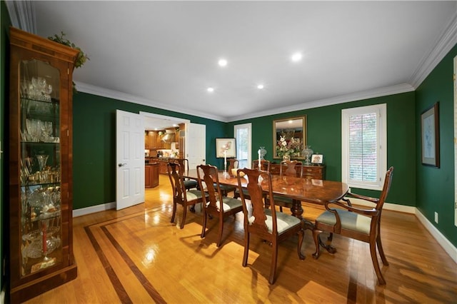 dining room with ornamental molding and light hardwood / wood-style floors