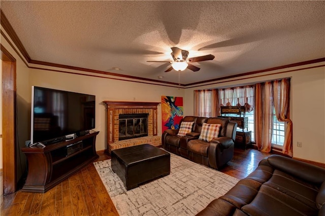 living room featuring a textured ceiling, ceiling fan, ornamental molding, a brick fireplace, and dark hardwood / wood-style flooring