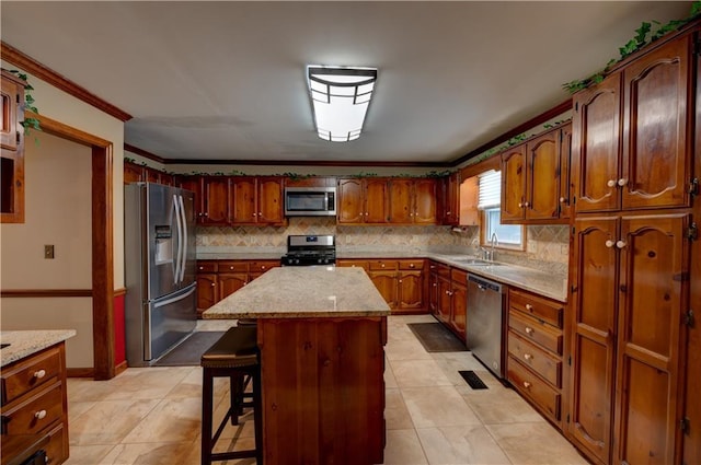 kitchen with a breakfast bar area, appliances with stainless steel finishes, ornamental molding, a kitchen island, and sink