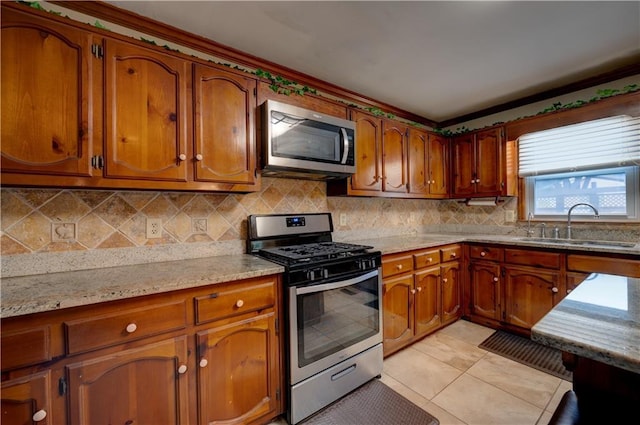 kitchen featuring light stone countertops, light tile patterned floors, tasteful backsplash, appliances with stainless steel finishes, and sink