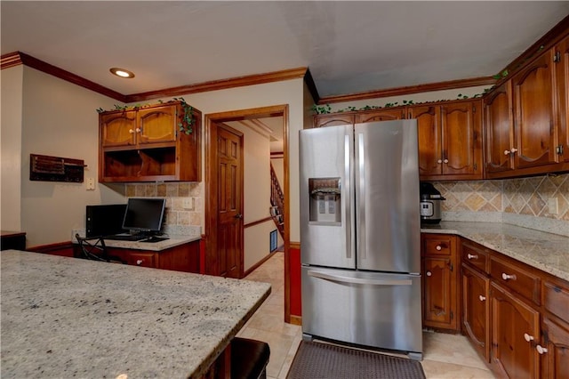 kitchen with light stone counters, stainless steel fridge, crown molding, backsplash, and light tile patterned flooring