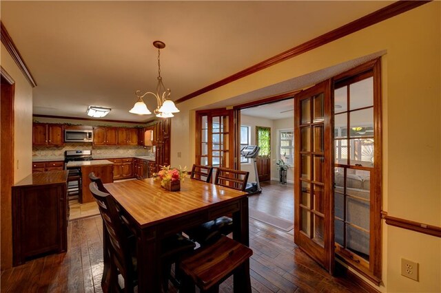 dining room featuring dark wood-type flooring, an inviting chandelier, french doors, and ornamental molding