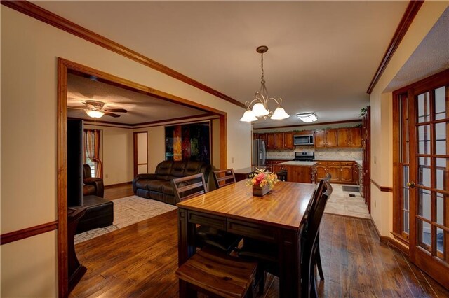 dining room featuring ornamental molding, dark wood-type flooring, and ceiling fan with notable chandelier