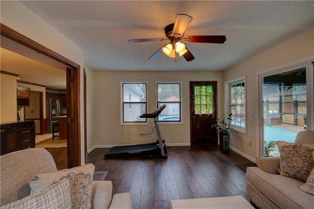 exercise room with a textured ceiling, ceiling fan, and dark hardwood / wood-style floors