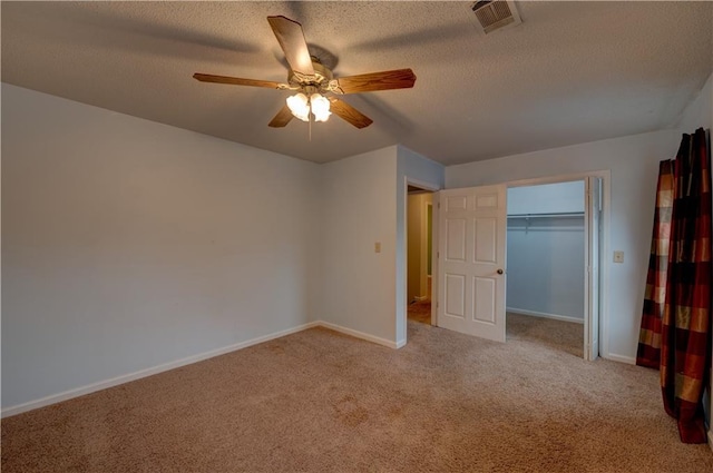 unfurnished bedroom with light colored carpet, ceiling fan, a textured ceiling, and a closet