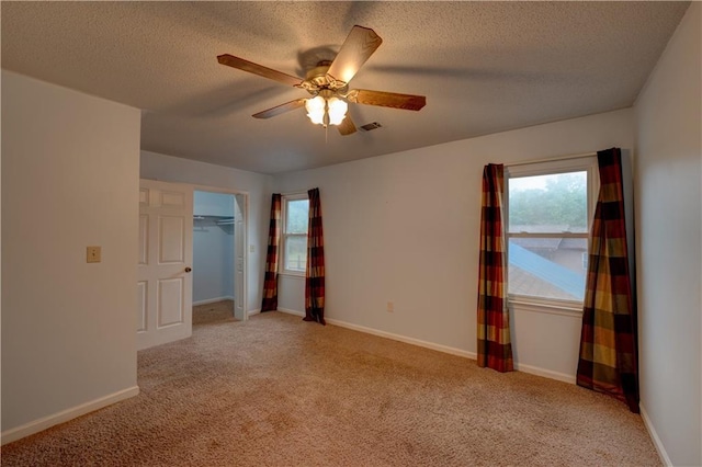 unfurnished bedroom featuring ceiling fan, light colored carpet, a closet, and a textured ceiling