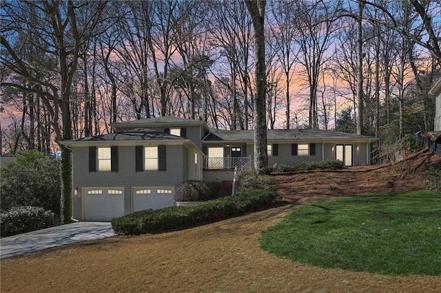 view of front facade with brick siding, a garage, a yard, and driveway