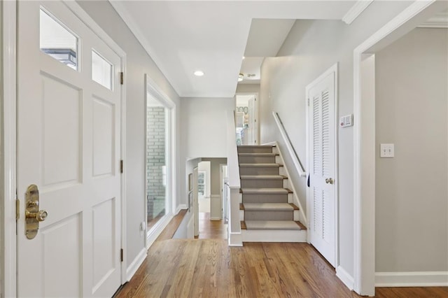 entryway featuring baseboards, stairway, ornamental molding, a wealth of natural light, and wood finished floors