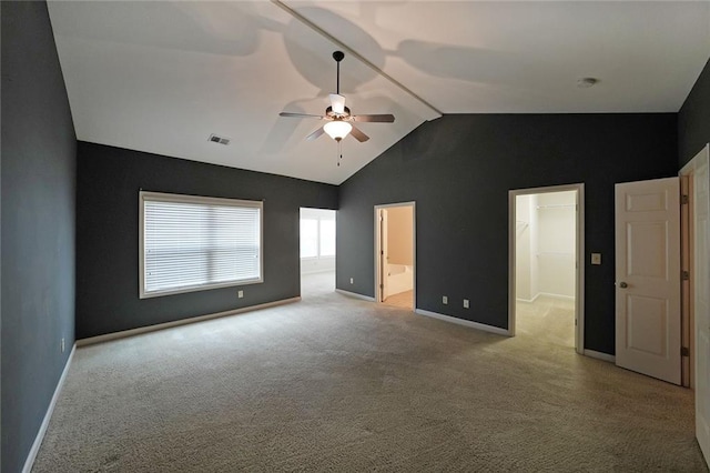 unfurnished bedroom with vaulted ceiling, connected bathroom, a spacious closet, ceiling fan, and light carpet