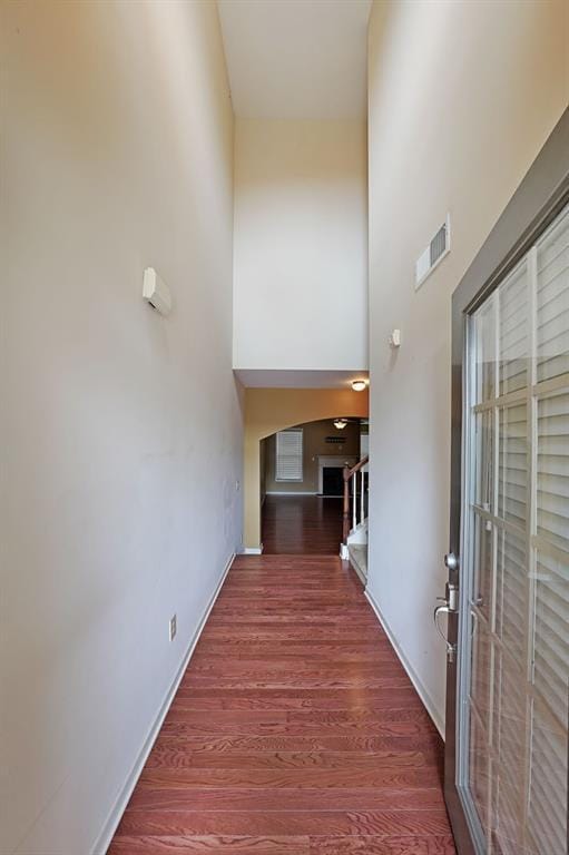 hallway with dark hardwood / wood-style floors and a towering ceiling