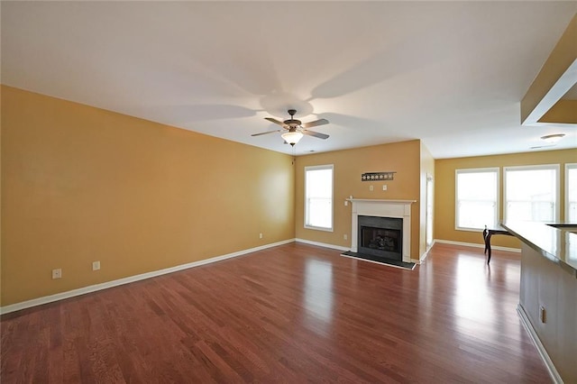 unfurnished living room featuring ceiling fan, wood-type flooring, and plenty of natural light