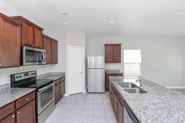 kitchen with light stone counters, light tile patterned flooring, appliances with stainless steel finishes, and sink