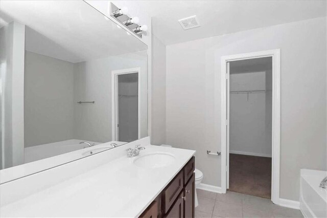 bathroom with toilet, vanity, a washtub, and tile patterned floors