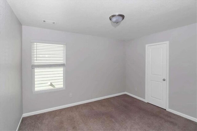 spare room featuring dark carpet