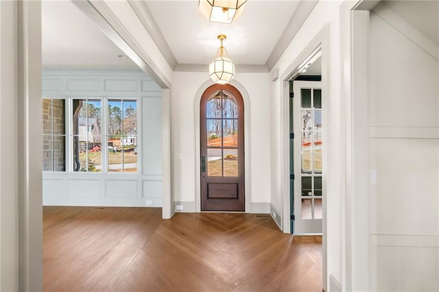 foyer entrance with a decorative wall, baseboards, and wood finished floors