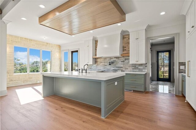 unfurnished living room featuring stairway, a sink, arched walkways, beam ceiling, and light wood finished floors
