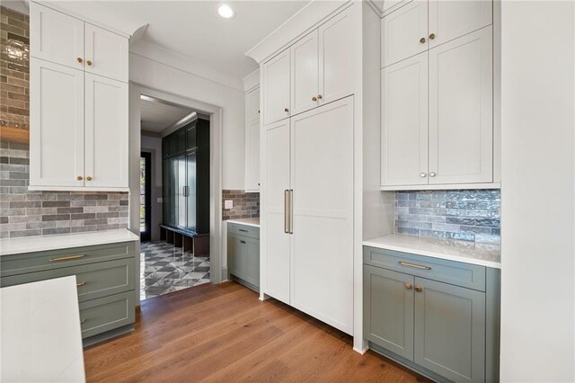 kitchen with crown molding, light countertops, light wood-style floors, and decorative backsplash