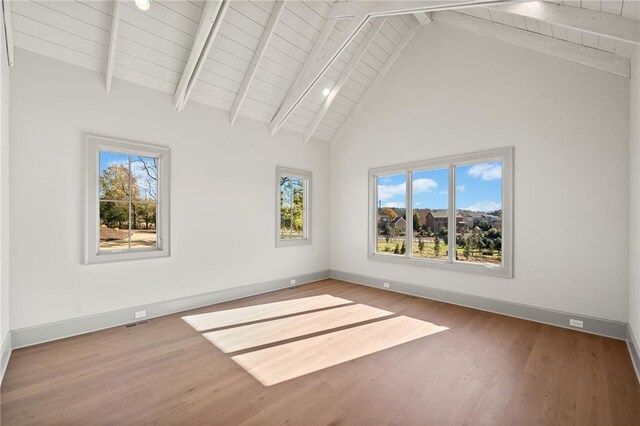 unfurnished room featuring baseboards, wood finished floors, and beam ceiling
