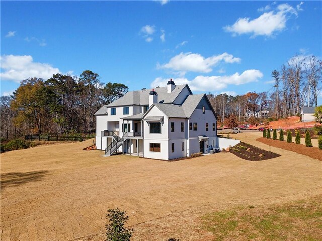 rear view of property featuring a lawn, stairway, fence, and a chimney