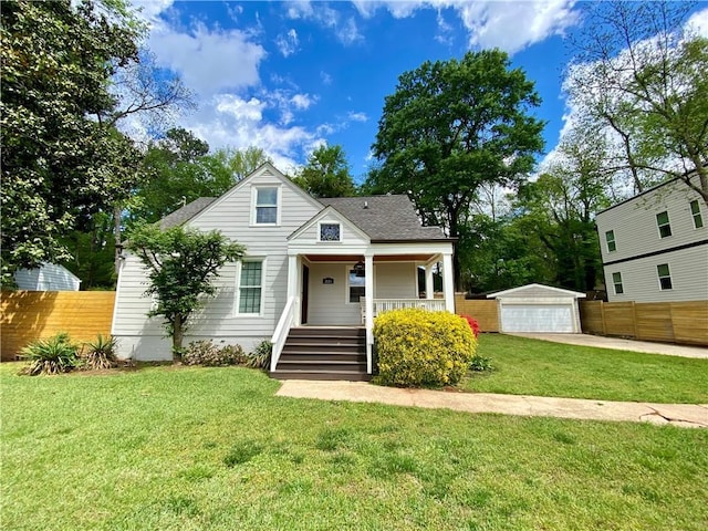 bungalow-style house with fence, covered porch, a front yard, and a detached garage