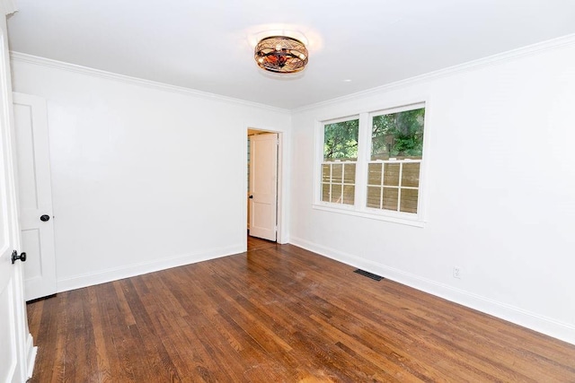spare room featuring baseboards, visible vents, ornamental molding, and wood finished floors
