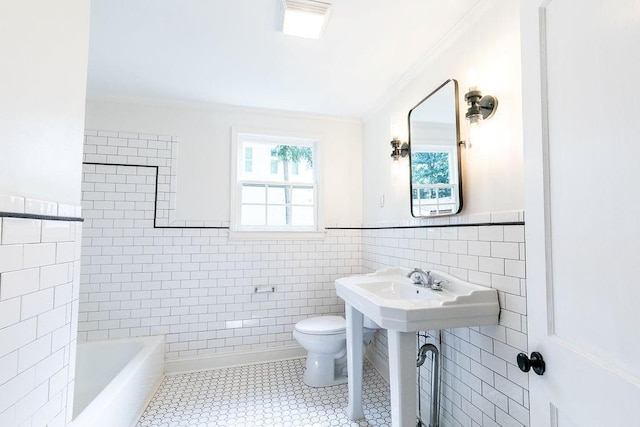 bathroom with crown molding, a bathtub, toilet, and tile walls