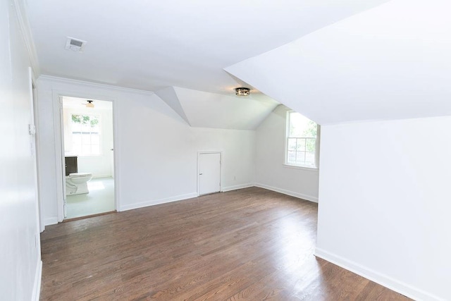 additional living space featuring baseboards, lofted ceiling, wood finished floors, and visible vents