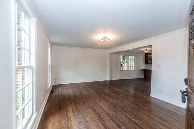 spare room featuring baseboards, ornamental molding, and dark wood-type flooring