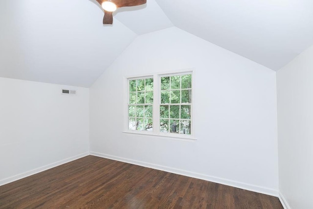 additional living space with ceiling fan, visible vents, vaulted ceiling, baseboards, and dark wood-type flooring