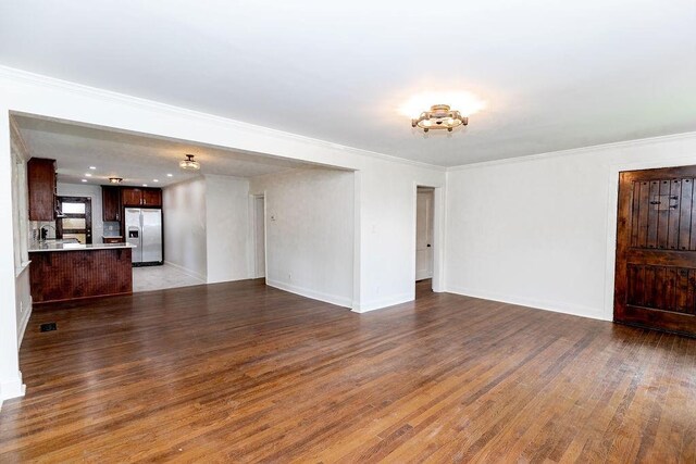 unfurnished living room featuring crown molding, baseboards, visible vents, and wood finished floors
