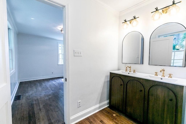 bathroom featuring visible vents, a sink, baseboards, and wood finished floors