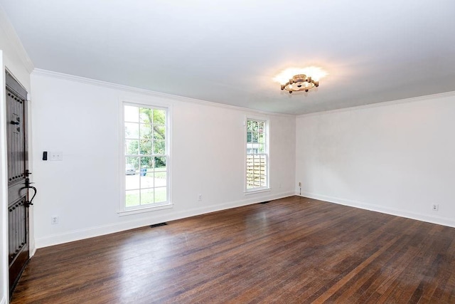 spare room featuring crown molding, plenty of natural light, and dark wood-type flooring