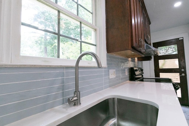 room details with decorative backsplash, dark brown cabinets, light countertops, a sink, and recessed lighting
