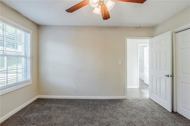 empty room featuring plenty of natural light, a ceiling fan, and carpet flooring