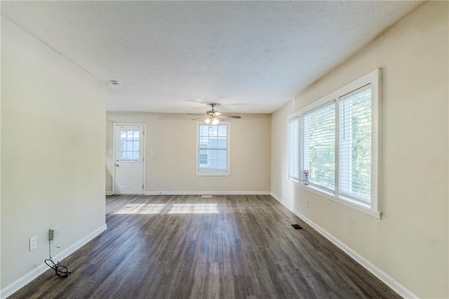 unfurnished living room featuring visible vents, baseboards, ceiling fan, dark wood-type flooring, and a textured ceiling