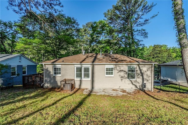 rear view of house with fence, a wooden deck, a yard, and brick siding