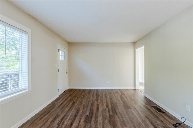 spare room with baseboards, dark wood-style floors, and visible vents